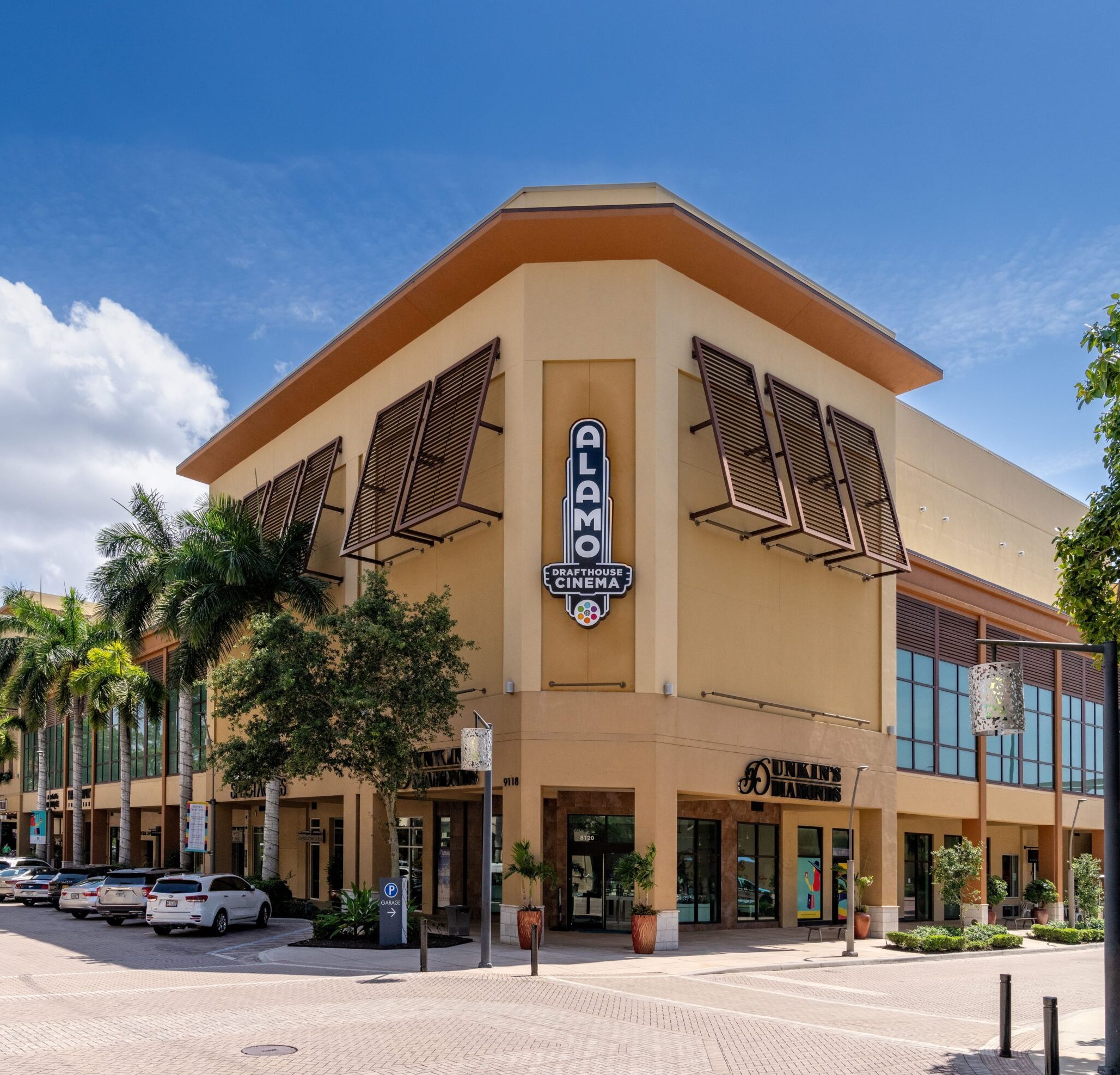 The front view of Alamo Drafthouse Cinema with nearby shops and parking spaces in the foreground.